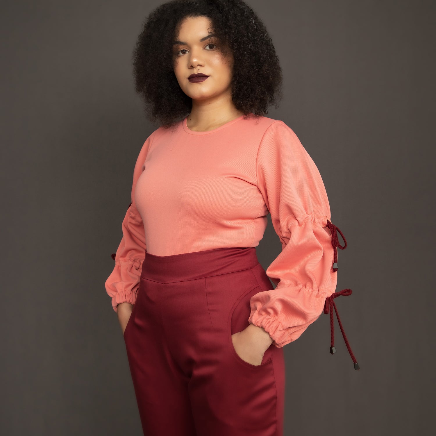 Salmon pink scuba top with drawstring detail on sleeves paired with burgundy trouser